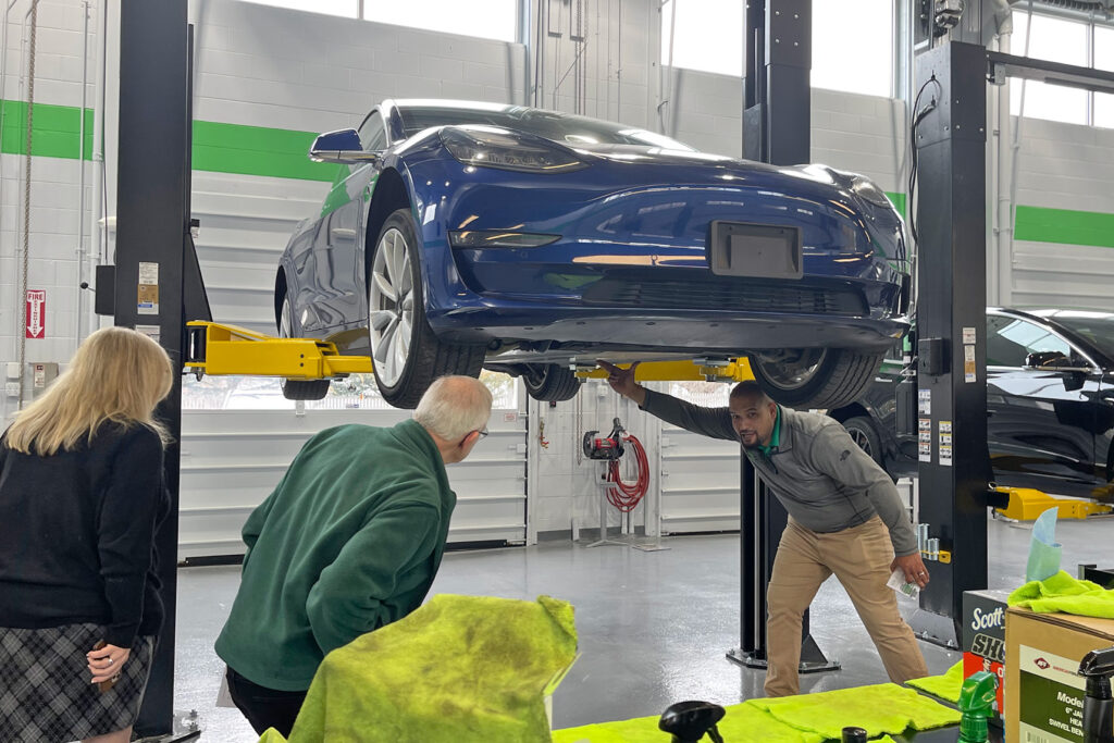 A Tesla on a lift, man giving demonstration